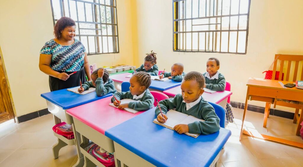 Kinder in einem Klassenzimmer in Tansania sitzen an Tischen und schreiben während des Unterrichts