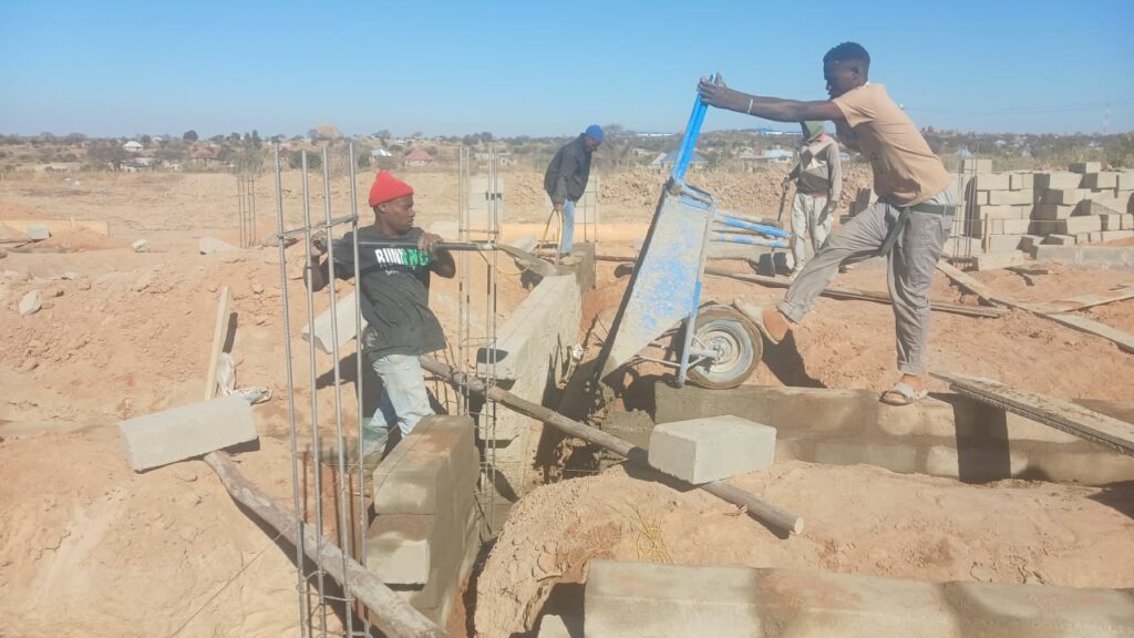 Bauarbeiten an der Secondary School in Nala, Tansania: Arbeiter betonieren die Fundamente der zukünftigen Schulgebäude auf dem gemeinsamen Schulgelände.